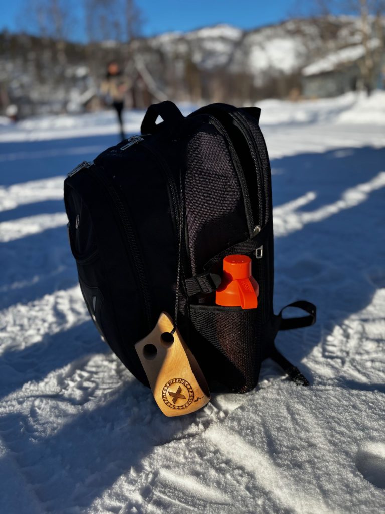 Rugzak in de sneeuw met houten mok tijdens een zakelijke reis Noorwegen